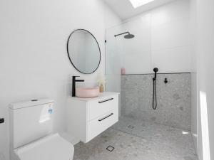 a white bathroom with a shower and a mirror at The Eddy Escape in Kingscliff +16 photos