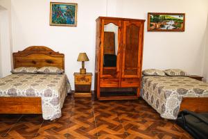 a bedroom with two beds and a tv and a mirror at Preloune Residences SA in Cap-Haïtien