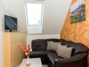 a living room with a black leather couch and a tv at Ferienhaus Kleindienst in Deutschlandsberg