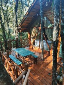 a wooden deck with a table and a bed in a tree house at Casa na Árvore in Rio dos Bugres