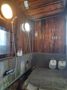 a bathroom with a shower and two toilets in it at 宿小町や in Senboku