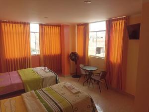a bedroom with two beds and a table and a window at Hostal Mitopampa in Lambayeque