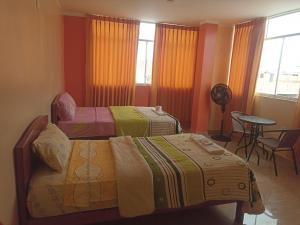 a bedroom with two beds and a table and a table at Hostal Mitopampa in Lambayeque