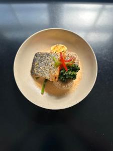a white plate with a piece of fish and broccoli at Grafton Hotel in Grafton