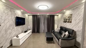 a living room with a black couch and a tv at Nid d'Amour in Strasbourg