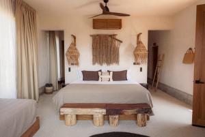 a bedroom with a large white bed with a wooden bench at Casa Yute Boutique Hotel Playa Aragon in San Agustinillo