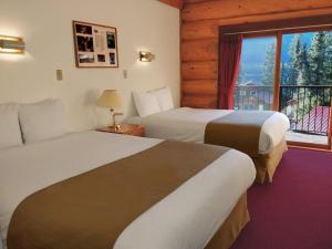 a hotel room with two beds and a window at Northern Rockies Lodge in Muncho Lake