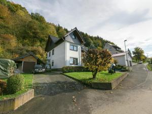 a white house with a tree in the driveway at Ferienwohnung in der Vulkaneifel in Winkel