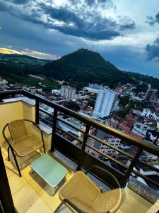 a balcony with chairs and a view of a city at Apê Moderno in Caxambu