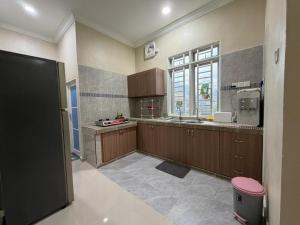a large kitchen with wooden cabinets and a window at Teratak Bonda in Temuh