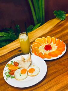 two plates of eggs and oranges and a glass of orange juice at Luu Ngai Condotel Quy Nhon in Quy Nhon