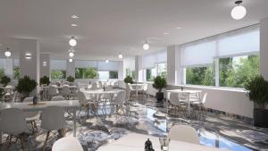 a restaurant with white tables and chairs and windows at Paradise Resort Evia, a member of Radisson Individuals in Eretria