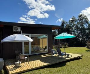 a deck with two chairs and two umbrellas at Rukachohan in Pucón