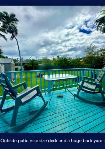 two chairs and a table on a deck at Surfers Dream Studio in Waianae