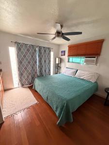 a bedroom with a green bed and a ceiling fan at Surfers Dream Studio in Waianae +9 photos