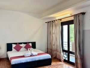 a bedroom with a bed with red pillows and a window at Matie Beach Hotel & Resort in Kao Kuil