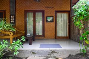 a porch of a house with a bench and doors at Kubu Pertiwi Pemuteran in Pemuteran
