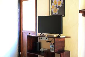 a flat screen tv on a shelf in a room at Kubu Pertiwi Pemuteran in Pemuteran
