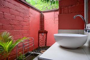 a bathroom with a white bowl sink in front of a red wall at Kubu Pertiwi Pemuteran in Pemuteran