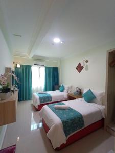 two beds in a room with green curtains at Che Wok Hotel in Kota Bharu +4 photos