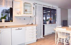 a kitchen with white cabinets and a table and a dining room at Beautiful Home In Simrishamn in Simrishamn
