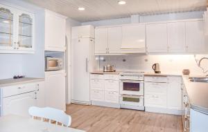 a white kitchen with white cabinets and a table at Beautiful Home In Simrishamn in Simrishamn