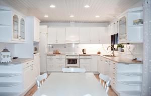 a kitchen with white cabinets and a table and chairs at Beautiful Home In Simrishamn in Simrishamn +8 photos