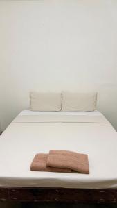 a white bed with a brown towel on it at Ayu Homestay - Room 4 in San Isidro