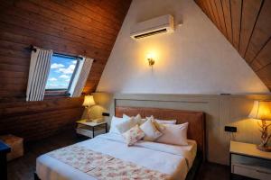 a bedroom with a bed with white sheets and a window at Kubana in Nuwara Eliya