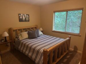 a bedroom with a bed with a striped comforter and a window at Creekside Cabin - Ski Chalet in Packwood