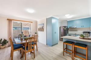 a kitchen and dining room with blue cabinets and a table at Waratah Retreat in Evans Head +10 photos