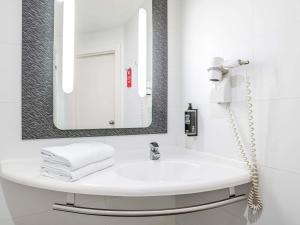 a white bathroom with a sink and a mirror at Ibis Bilbao Barakaldo in Barakaldo