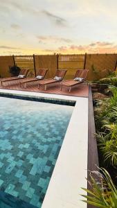 a pool with lounge chairs next to a fence at Tides Apartments in Nadi