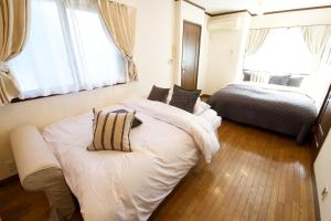 a bedroom with two beds and two windows at Forest Inokashira in Mitaka
