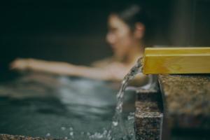 a man in a swimming pool with water coming out of azi at Villa El Cielo Myoko in Myoko