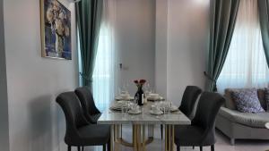 a dining room table with black chairs and a table with wine glasses at บ้านมั่งมี ขอนแก่น in Ban Si Than
