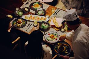 a group of people sitting around a table with food at Villa El Cielo Myoko in Myoko