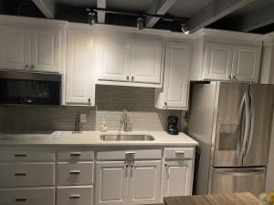 a kitchen with white cabinets and a stainless steel refrigerator at Tiny home living!! First floor condo! in Panama City Beach