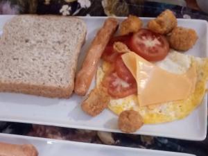 ein Teller mit Frühstücksessen mit Eiern, Wurst und Brot in der Unterkunft GenAyah Hotel & Safari in Mtimba