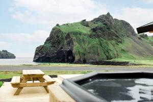 a picnic table and a bath tub in front of a mountain at Luxury Ocean Villas in Vestmannaeyjar