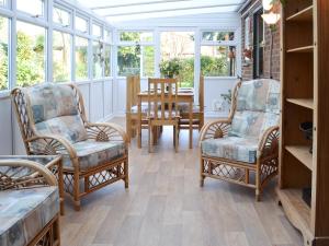 a conservatory with chairs and a table and windows at Pam's Plaice in Offord Cluny
