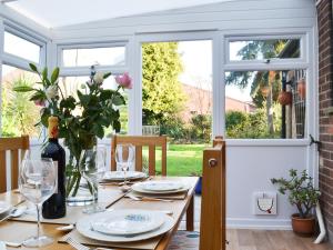 a table with plates and glasses and a vase with flowers at Pam's Plaice in Offord Cluny