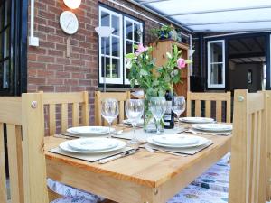 a wooden table with plates and glasses and a clock at Pam's Plaice in Offord Cluny