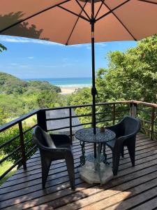 a table and chairs on a deck with an umbrella at Amapondo in Port St. Johns
