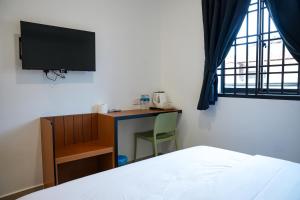 a bedroom with a bed and a desk with a television at TEBRAU 11 Guesthouse in Johor Bahru