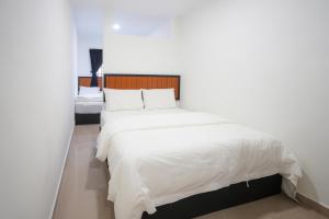 a bedroom with a large bed with white sheets at TEBRAU 11 Guesthouse in Johor Bahru