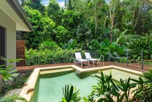 a swimming pool in a garden with two chairs at Belle Escapes Samaya in Palm Cove