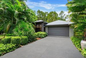 a house with a garage and palm trees at Belle Escapes Samaya in Palm Cove