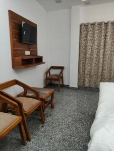 a room with two chairs and a tv and a bed at Prithvi hotel and restaurant in Mussoorie