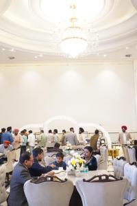 a group of people sitting at tables in a restaurant at Hotel The Grand Mirage in Bathinda +25 photos